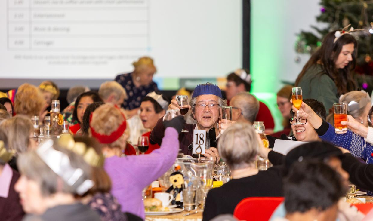 One Day at Christmas attendees raising a glass at table